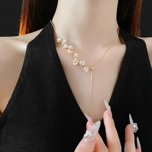 Detail of a gold Y-shaped necklace with white flower charms on a model with black clothing