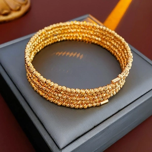 Close-up of multilayered gold-plated beaded bangle on a luxury leather jewelry case