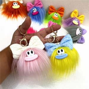 Dettaglio di portachiavi a forma di mostro in peluche colorato con fiocchi e ganci