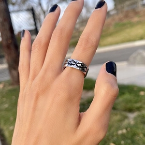 Close-up of titanium steel ring with black thorn pattern worn on hand in outdoor light