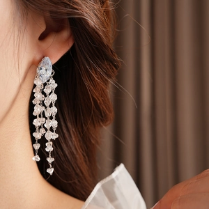 Close-up of sparkling long fringe earrings with drop crystal on a female model