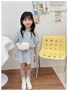 Detail view of a cute white dolphin shaped crossbody bag on a child's gray knit dress