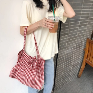 Close-up of red and white gingham fabric tote bag with lace-up straps in sunlight