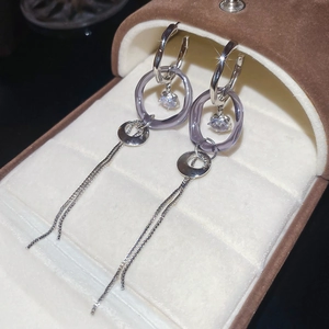 Gros plan de boucles d'oreilles à pompons en C avec pierres violettes en écrin