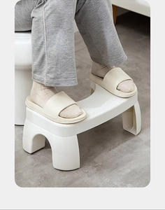 White ergonomic plastic toilet footstool with non-slip surface used in bathroom