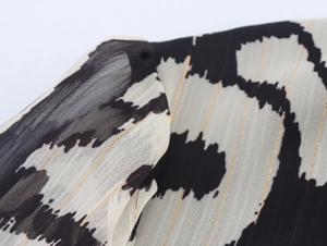 Detailed close-up of chiffon fabric with black and white animal print and golden threads