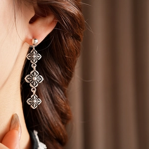 Detail of vintage silver floral drop earrings worn by model for retro aesthetic