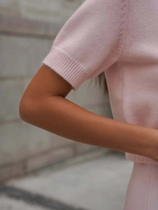 Gros plan détaillé sur la maille fine et les finitions du pull rose à manches courtes