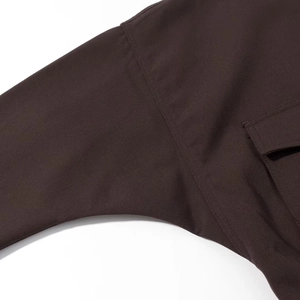 Close-up of premium stitching and pocket detail on a dark brown long-sleeve jacket