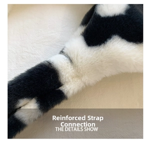 Detail of reinforced strap connection on plush cow print handbag with soft faux fur texture