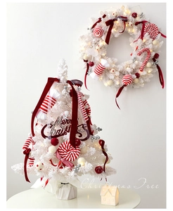 Close-up of white Christmas tree with red velvet bows and candy cane ornaments