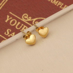 Polished gold heart stud earrings on vintage props providing an elegant aesthetic
