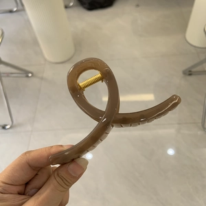 Detailansicht einer großen braunen Haarklammer mit einer starken goldenen Metallfeder