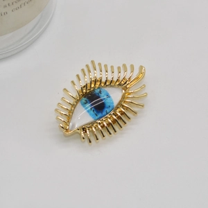 Vintage golden metal evil eye brooch with blue enamel and radiant lash design