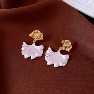 Detailed view of ginkgo leaf earrings with gold texture and white teardrop stone