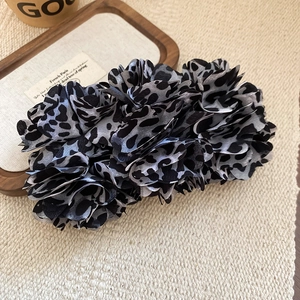 Macro shot of fabric leopard print hair claw with detailed pleated floral texture