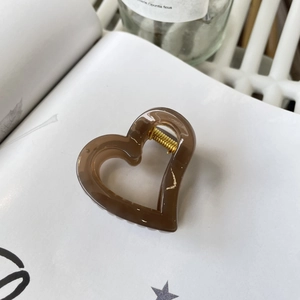 Elegant amber brown hollow heart hair claw clip made of acrylic on a white book page