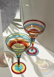Artistic detail of hand-painted colorful striped margarita glass with vibrant light shadows