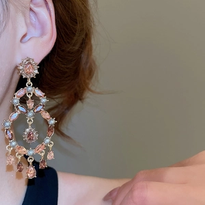 Close-up of chandelier style earrings with pink rhinestones and teardrop pearls