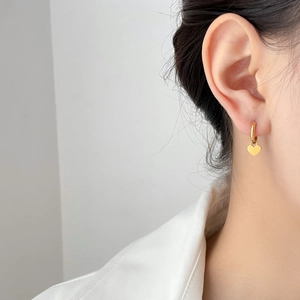 Minimalist gold heart dangle hoop earrings worn by a model for a stylish elegant look