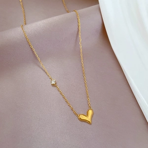 Macro shot of gold-plated titanium heart necklace with zircon inlay on soft silk