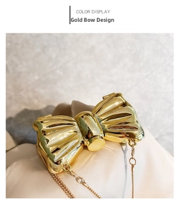 Macro detail of golden bow-shaped evening bag featuring mirror finish and metal chain