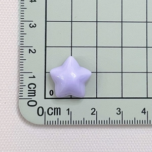 Size reference of 1.8cm purple macaron star resin bead on a green grid measurement mat