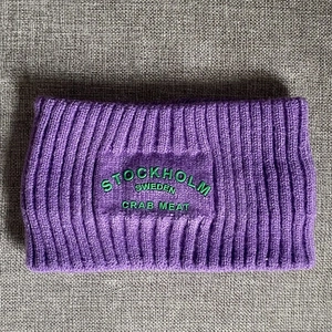 Detail eines lila gerippten Strickstirnbands mit grüner Stockholm-Stickerei in Kontrast