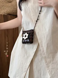 Detail of bohemian mini crossbody bag featuring coconut shell discs and white floral accent