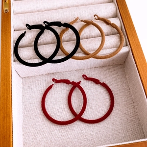 Three pairs of vintage-style flocked round hoop earrings in black, camel, and burgundy
