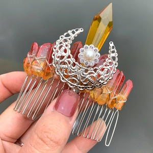 Close-up of handmade silver moon hair comb featuring natural red and yellow crystals