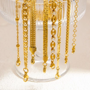 Stack of gold stainless steel Cuban and snake chains hanging on a glass texture