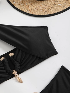 Close-up of black bikini fabric with pleated details and a luxury gold metal ring accessory