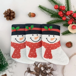 Close-up of three snowman Christmas mini stockings with festive pine and berry decor