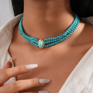 Detail of bohemian turquoise beaded layered necklace on white linen shirt