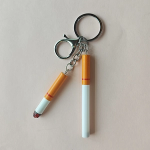 Miniature realistic cigarette keychain with silver metal chain and lobster clasp on pink background