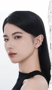 Close-up of golden wavy ear cuff and silver star zircon earring on model's ear