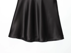 Gros plan montrant la texture luxueuse du tissu satiné noir et sa finition lisse et soyeuse