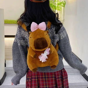 Plush brown Capybara backpack with pink bow and small bunny doll on indoor stairs