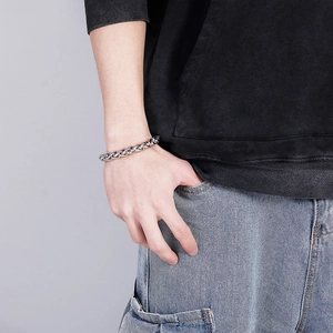 Silver stainless steel men's chain bracelet styled on a male wrist in a casual pose