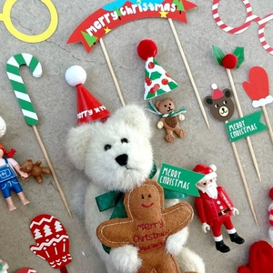 Detailed flat lay of Christmas cake toppers including teddy bear, Santa, and merry banners