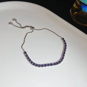 Detail of adjustable silver bolo bracelet with purple zircon stones on a ceramic tray