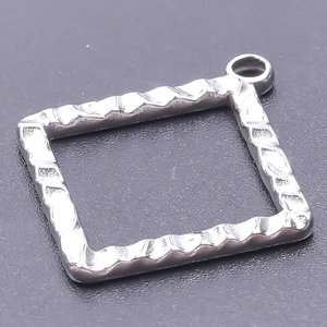 Nahaufnahme eines silbernen quadratischen Metallanhängers mit Wellenstruktur für DIY