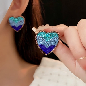 Macro detail of vintage heart stud earrings with blue gradient rhinestones in silver