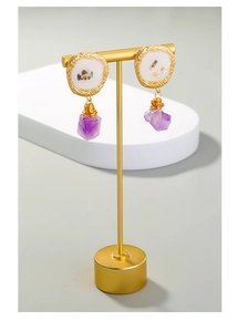 Detail of purple amethyst drop earrings with golden embossed discs and shell inlay