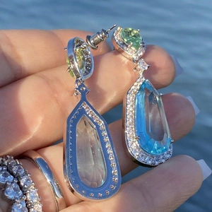 Macro detail of tear-drop aquamarine wedding earrings and pavé rings in natural sunlight