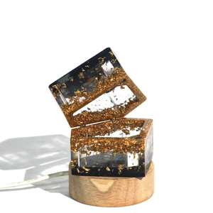 Detailed view of DIY resin jewelry box with gold foil flakes and a wooden LED light base