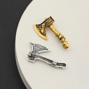 Detailed view of gold and silver axe brooches with intricate relief and pin backing