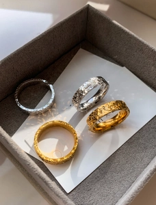 Macro detail of four textured gold and silver plated rings in a minimalist wide design