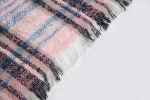 Close-up of checkered plaid scarf fabric texture featuring pink and blue stripes with tassels